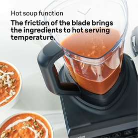 Black blender with clear jug filled with hot tomato soup, bowls of soup styled alongside, demonstrating hot soup blending function
