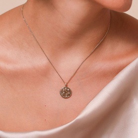 Model with Astrid & Miyu Libra Zodiac Pendant 18k Gold-Plated Necklace, gold-tone disc with crystal constellation detailing on delicate chain