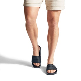 Model wearing KG by Kurt Geiger Ibiza Slides in black, slip-on open-toe design with wide foot strap, styled with beige shorts