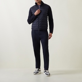 Model wearing Moncler Padded Quilted Zip Cardigan in navy, with knitted sleeves and high collar, styled with navy trousers and trainers