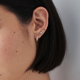 Model with Missoma Silver Pave Claw Huggie Earrings in sterling silver with cubic zirconia stones, worn with a small stud earring above