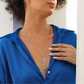 Model wearing Newbridge Wish Feather Pendant Necklace in silver with rose gold feather pendant on chain, styled with blue shirt