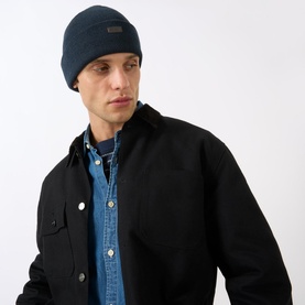 Model with Barbour Healey Beanie Hat in navy, featuring turned-up brim and logo detail, styled with black overshirt and denim shirt