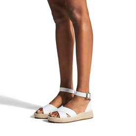Model wearing Carvela Catch Flatform Espadrilles in white, featuring crossed toe straps, buckled ankle strap, and espadrille sole