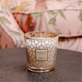 Baobab My First Candle Miami in pink, gold geometric glass vessel, styled on dark surface with floral backdrop