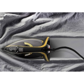 Tefal Ultimate Turbo Pro steam iron in black and gold, resting on grey fabric with braided cord visible