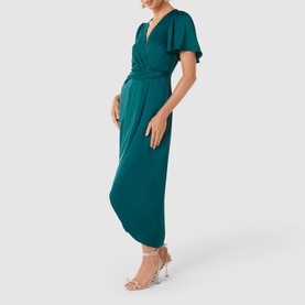 Model wearing Forever New Estelle Satin Flutter Sleeve Midi Dress in green, with wrap front, cinched waist, styled with silver heeled sandals