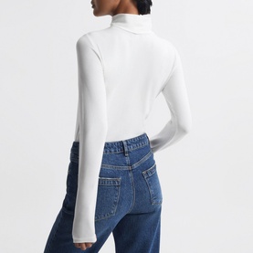 Model wearing Reiss Piper Roll Neck Fitted Top in white, long sleeves, styled with blue denim jeans. Rear view