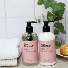 Max Benjamin French Linen Water hand wash and lotion duo in pink pump bottles, styled with folded towels and eucalyptus on a bathroom shelf