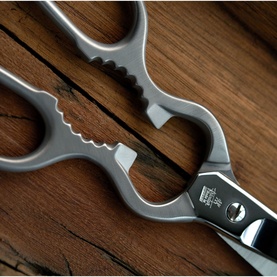 Zwilling Stainless Steel Multi-purpose Shears in silver, close-up of forged stainless steel handles and pivot on wooden surface