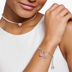 Model with Thomas Sabo Palm Tree Shaped Charm Pendant in sterling silver with pink stone, worn on a chain bracelet with heart charm