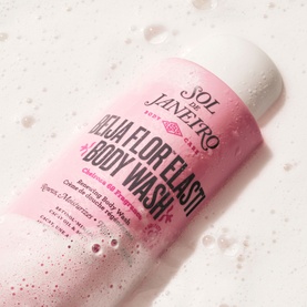 Sol De Janeiro Beija Flor Body Wash in pink bottle with foam bubbles on white surface