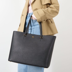 Model carrying Lauren Karly Large Tote Bag in black crosshatch leather with gold-tone hardware and dual carry handles, styled with camel blazer and