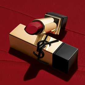 YSL Rouge Pur Couture Lipstick in deep red, open bullet resting on gold monogram case against red background