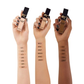 Three hands with varying skin tones holding YSL All Hours Precise Angles Concealer bottles, showing shade range swatches on wrists