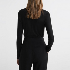 Model wearing Reiss Brady Top in black with long sleeves and layered cuffs, styled with black tailored trousers. Rear view