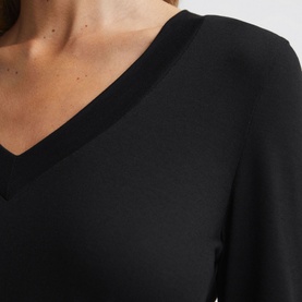 Model wearing Reiss Brady Top in black, close-up showing V-neckline and smooth fabric with tonal stitching detail