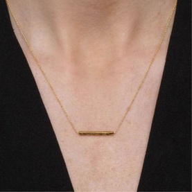 Model with Juvi Horizon Short Bar Necklace in gold; hammered bar pendant with hand-textured finish on fine chain, 18ct yellow gold vermeil