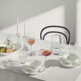 Waterford Lismore Castle clear crystal glassware styled on a white dining table with candles, wine glasses, pitcher, and white dinnerware