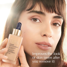 Model with Est&eacute;e Lauder Futurist SkinTint Serum Foundation SPF 20 30ml dropper bottle, shown close-up with natural glowing skin finish