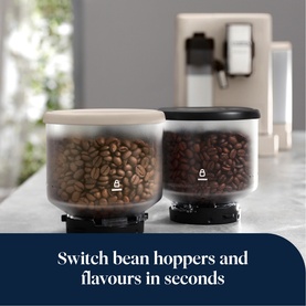 Delonghi Rivelia Automatic Compact Bean To Cup in beige with two swappable bean hoppers filled with coffee beans on a counter