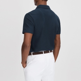 Model wearing Reiss Felix Half-Zip Polo Shirt in blue, textured cotton, short sleeves, styled with white trousers. Rear view