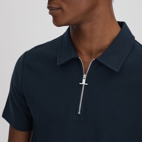 Model wearing Reiss Felix Half-Zip Polo Shirt in blue cotton with silver-tone half-zip fastening and collared neckline