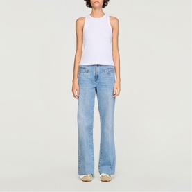 Model wearing Sandro Logo Tank Top in white ribbed cotton with round neck, styled with light blue wide-leg jeans.