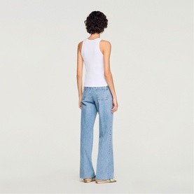 Model wearing Sandro Logo Tank Top in white ribbed cotton, styled with light blue wide-leg jeans. Rear view showing sleeveless cut and straight hem.