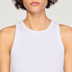 Model wearing Sandro Logo Tank Top in white, round neck, sleeveless ribbed cotton design with embroidered logo detail
