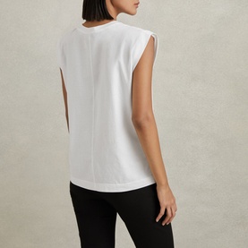 Model wearing Reiss Morgan Solid T-Shirt in white, showing raised back seam detail, cap sleeves and straight hem, styled with black trousers
