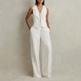 Model wearing Reiss Lori High-Rise Wide-Leg Trousers in white, styled with a matching white tailored waistcoat