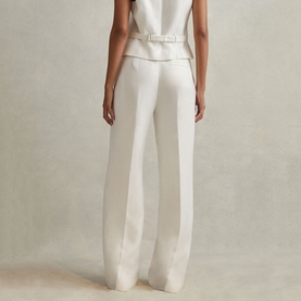 Model wearing Reiss Lori High-Rise Wide-Leg Trousers in white, styled with a matching white sleeveless top. Rear view showing wide-leg silhouette