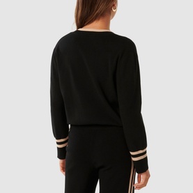 Model wearing Forever New Hattie Knit Sweater in black, rear view, with contrast stripe cuff trims, styled with matching black wide-leg trousers