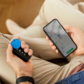 Chipolo ONE Bluetooth Item Finder in blue, attached to keys, held alongside a smartphone displaying the Chipolo tracking app