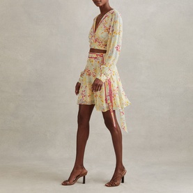 Model wearing Reiss Lyla Floral Pink Mini Skirt with contrast trims and tie waist, styled with a matching floral top and tan heeled sandals