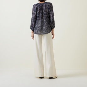 Model wearing Part Two Elsia Floral Relaxed Fit Blouse in navy floral print, relaxed fit, flared cuffs, styled with wide-leg cream trousers
