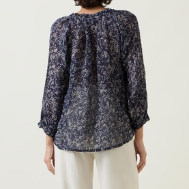 Model wearing Part Two Elsia Floral Relaxed Fit Blouse in navy floral print, back view, with white wide-leg trousers