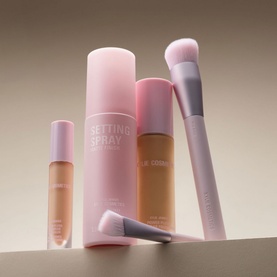 Kylie by Kylie Jenner Power Plush Longwear Foundation shown with matching setting spray and two makeup brushes in pink packaging