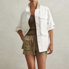 Model wearing Reiss Violet Ribbed Tank Top in Green, styled with a white utility jacket and khaki drawstring shorts