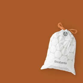 Brabantia PerfectFit Bin Bags 12L in white with orange tie-tape closure, circular pattern design, displayed against terracotta background