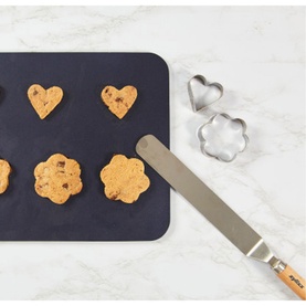Zyliss Angled Palette Knife in stainless steel, shown with heart and paw-shaped cookies on dark baking mat alongside metal cookie cutters
