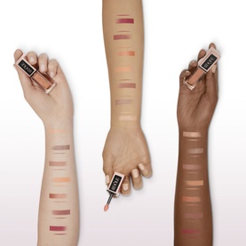 Three arms showing Lanc&ocirc;me Id&ocirc;le Tint Liquid Eye Blusher swatches across skin tones, with bottles held, displaying nude to rose shades