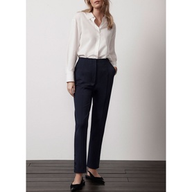 Model wearing Mint Velvet Blue Slim-Leg Tailored Trousers, ankle grazer length with split hems, styled with a white shirt and black flat shoes