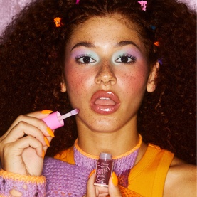 Model with Too Faced Kissing Jelly Lip Oil Gloss in Grape Soda, 4.5ml, applying gloss with wand applicator