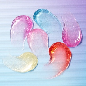 Too Faced Kissing Jelly Lip Oil Gloss swatches in six shades including pink, blue, clear, red, and orange on a gradient background