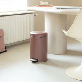 Brabantia NewIcon Pedal Bin 12L in taupe, styled in a modern home interior beside a white dining table and radiator