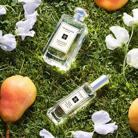 Jo Malone London English Pear & Sweet Pea Cologne 100ml and 30ml bottles on grass with fresh pears and white flower petals