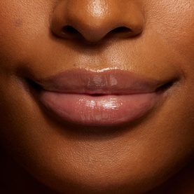 Close-up of lips wearing Kylie Cosmetics Lip Butter, showing a glossy, hydrated finish on deep skin tone