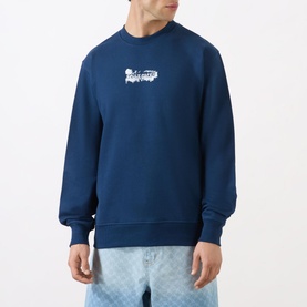 Model wearing Daily Paper Scratch Logo Sweatshirt in blue, crew neck with white graphic logo, styled with light blue patterned trousers